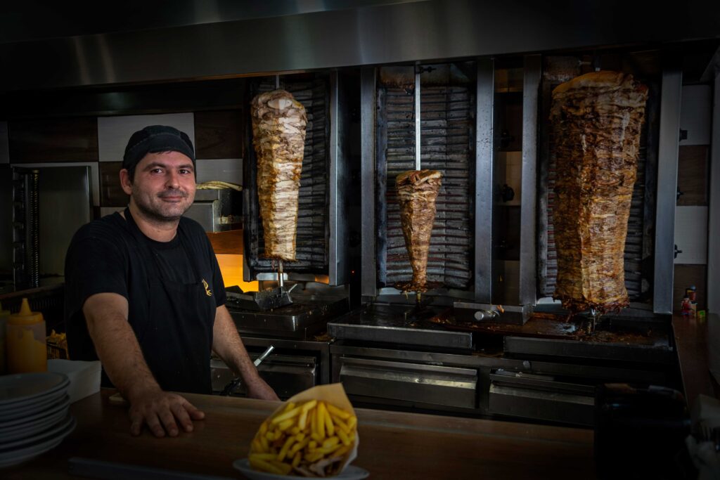 Un cheff posa junto a una enorme porción de pitá, en Heraclión