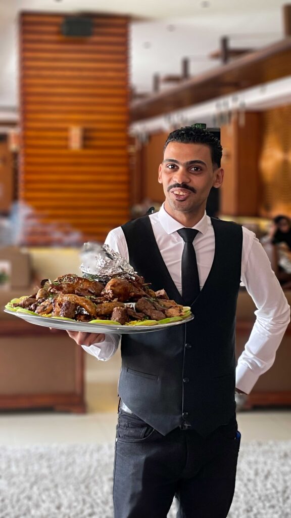 El mesero posando orgulloso con una parrillada local